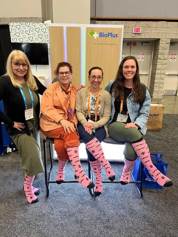 4 people wearing pink socks with mustaches at a conference