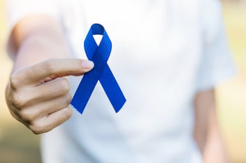 woman holding a blue ribbon for Colorectal Cancer Awareness Month